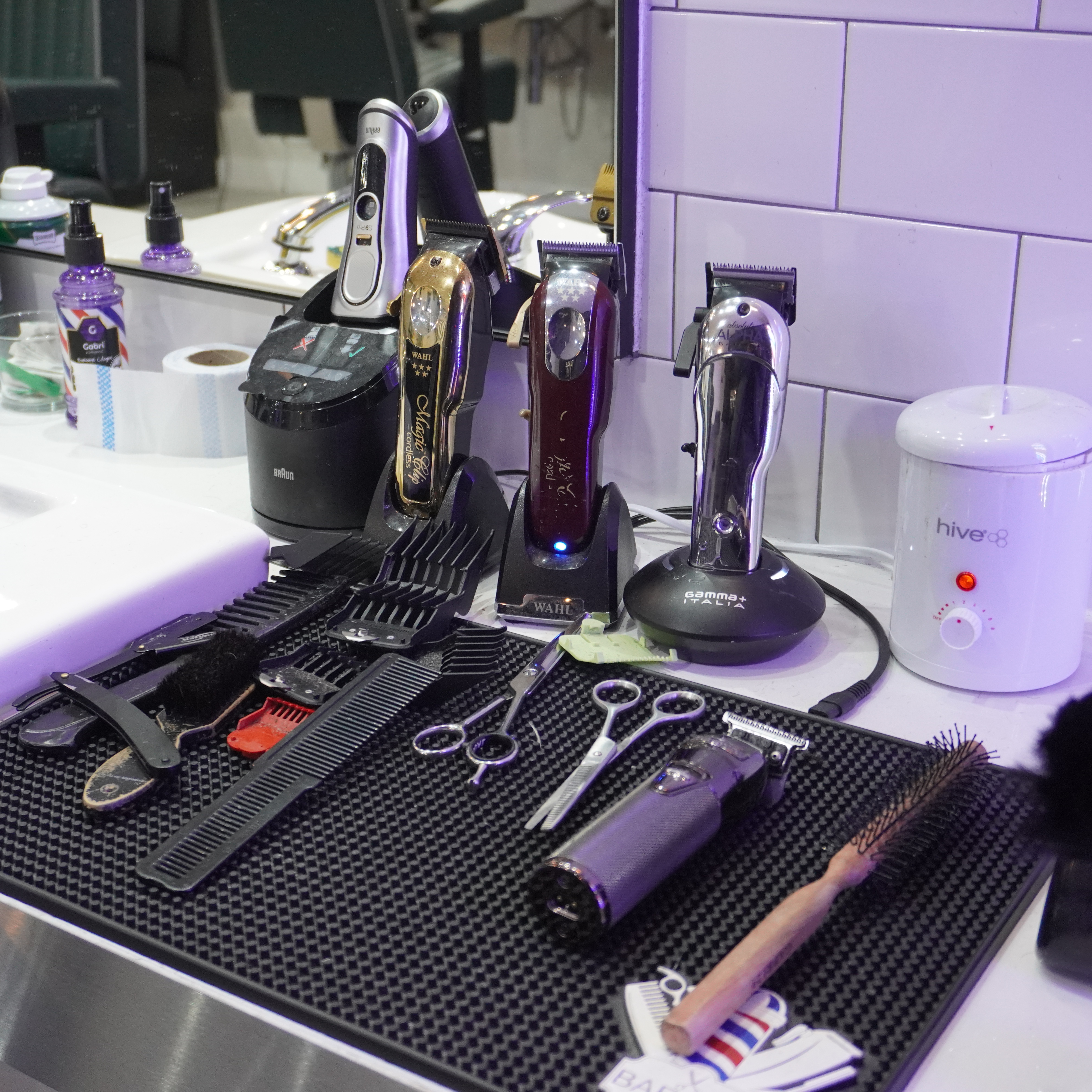 Assortment of barber tools including clippers, scissors, and combs on a salon workstation.